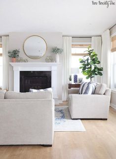 a living room with two couches and a fireplace in the corner, along with potted plants