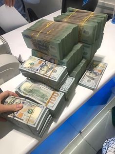 stacks of money sitting on top of each other in front of a computer desk with people working behind them