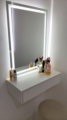 a white vanity with a lighted mirror and bottles on the top shelf next to it