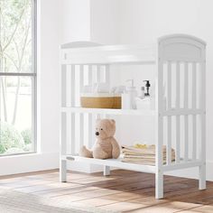 a white bunk bed with a teddy bear on the bottom shelf in front of it