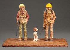 two figurines are standing on top of a wooden plaque with a dog and an old man