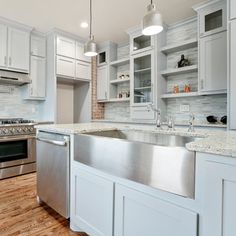 a large kitchen with white cabinets and stainless steel appliances on the counter top, along with wooden floors