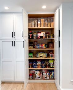 an organized pantry with white cabinets and wood floors