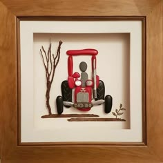 a red and black car is in a shadow box with a tree on the side