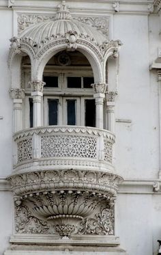 an ornate balcony on the side of a white building