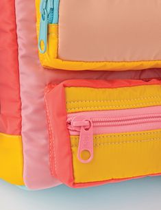 the back side of a pink and yellow backpack with zippers on it's sides