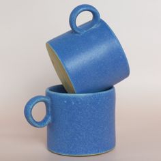 two blue coffee cups stacked on top of each other with one cup in the middle