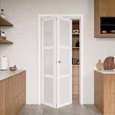 an open door in the middle of a kitchen with wooden cabinets and counter tops on both sides