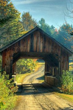 a wooden covered bridge over a dirt road