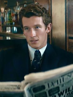 a man in a suit and tie reading a newspaper