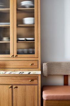 a wooden cabinet sitting next to a chair in a room with white walls and flooring