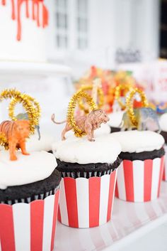 cupcakes with white frosting and gold decorations on them are sitting on a table