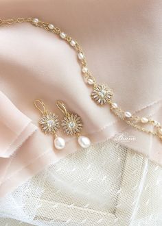 the bride's jewelry is laying on her wedding dress, and it looks like they are wearing pearls