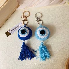 two crocheted keychains with tassels and eyeballs on them