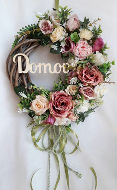 a wreath with flowers and the word domo on it hanging from a white wall