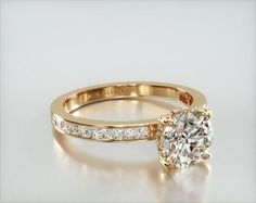 a yellow gold engagement ring set with a round brilliant cut diamond in the center and side stones on each band