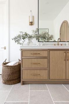 a bathroom with a sink, mirror and basket on the floor