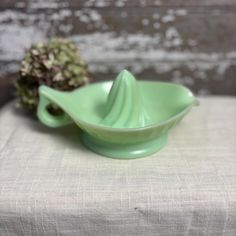 a green bowl sitting on top of a table next to a piece of artichoke