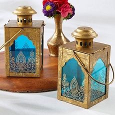 three small lanterns sitting on top of a wooden table next to a vase with flowers in it