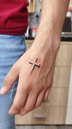 a person with a cross tattoo on their hand