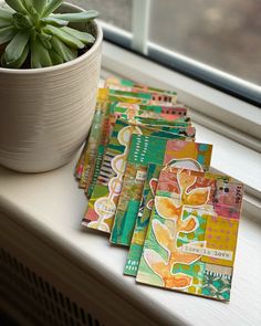 a potted plant sitting on top of a window sill next to some cards