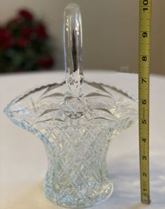 a clear glass vase with a measuring tape next to it