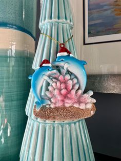 a blue vase with two dolphins on it and pink corals in the bottom right corner