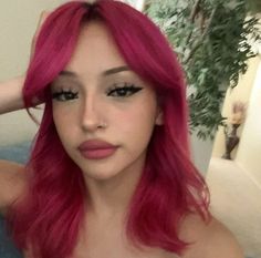 a woman with pink hair is taking a selfie in front of the camera and has her hand on her head