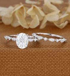 a close up view of a diamond ring on a table with flowers in the background