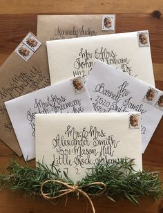 four envelopes with handwritten calligraphy on them, tied to a wooden table