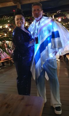 a man and woman standing next to each other in front of a table with lights on it