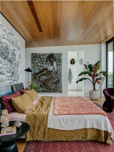 a bedroom with a large bed and paintings on the wall next to it's windows