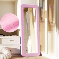 a large pink mirror sitting on top of a wooden floor next to a white dresser