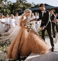 a bride and groom are walking down the aisle at their wedding ceremony with guests in the background