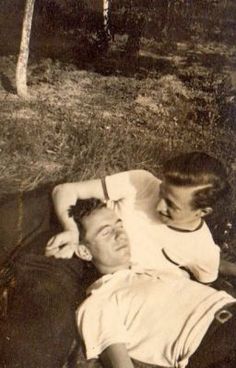 an old black and white photo of two people laying on the ground