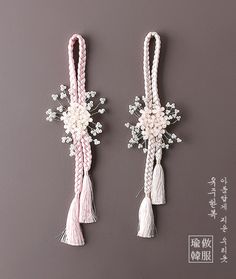 two tassels with flowers and beads hanging on the wall next to each other