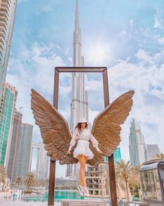 a man and woman posing in front of an angel statue with the burj building in the background