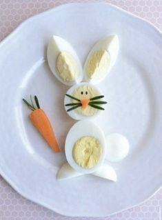 an easter bunny made out of eggs and carrots on a white plate with pink polka dot tablecloth