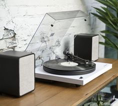 a record player sitting on top of a wooden table next to a potted plant