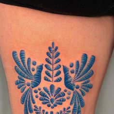 a woman's thigh with a blue tattoo design on it