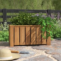 a wooden planter sitting on top of a stone floor next to a hat and shovel