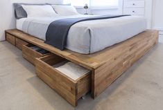 a bed that has drawers underneath it in a room with carpeted flooring and white walls