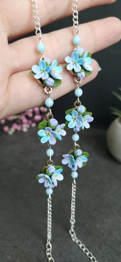 a pair of earrings with blue flowers hanging from chains