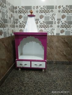 a toy stove with two drawers on top of it in front of a tiled wall