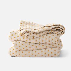 three blankets stacked on top of each other in yellow polka dotty print, with one folded