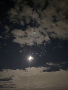 the sun is shining brightly in the dark sky above some clouds and water, as seen from an ocean shore