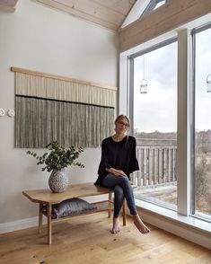 a woman sitting on a bench in front of a window