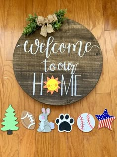 a wooden sign that says welcome to our home with some magnets on the floor