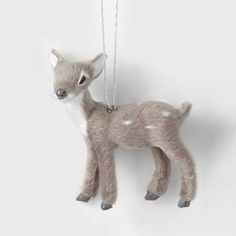 a small deer ornament hanging from a chain on a white wall with a gray background