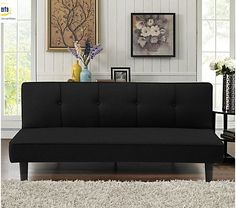 a black futon sofa in a living room with white carpet and pictures on the wall